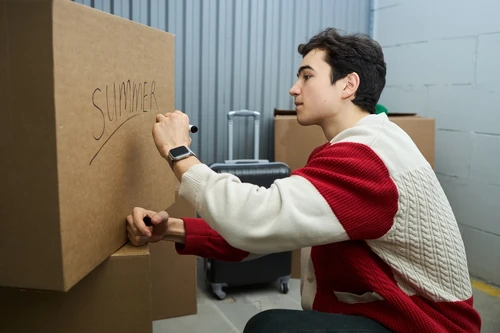 Student labeling a cardboard box that says "Summer"